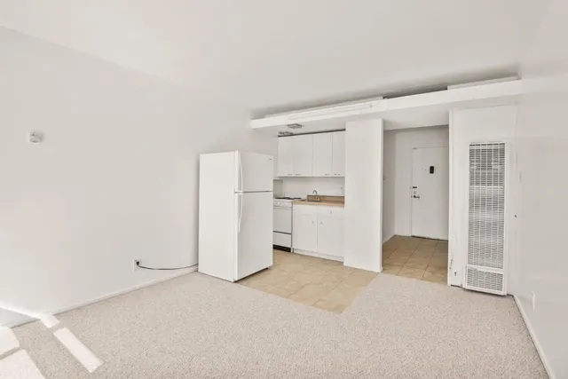 a view of a kitchen with refrigerator and white cabinets