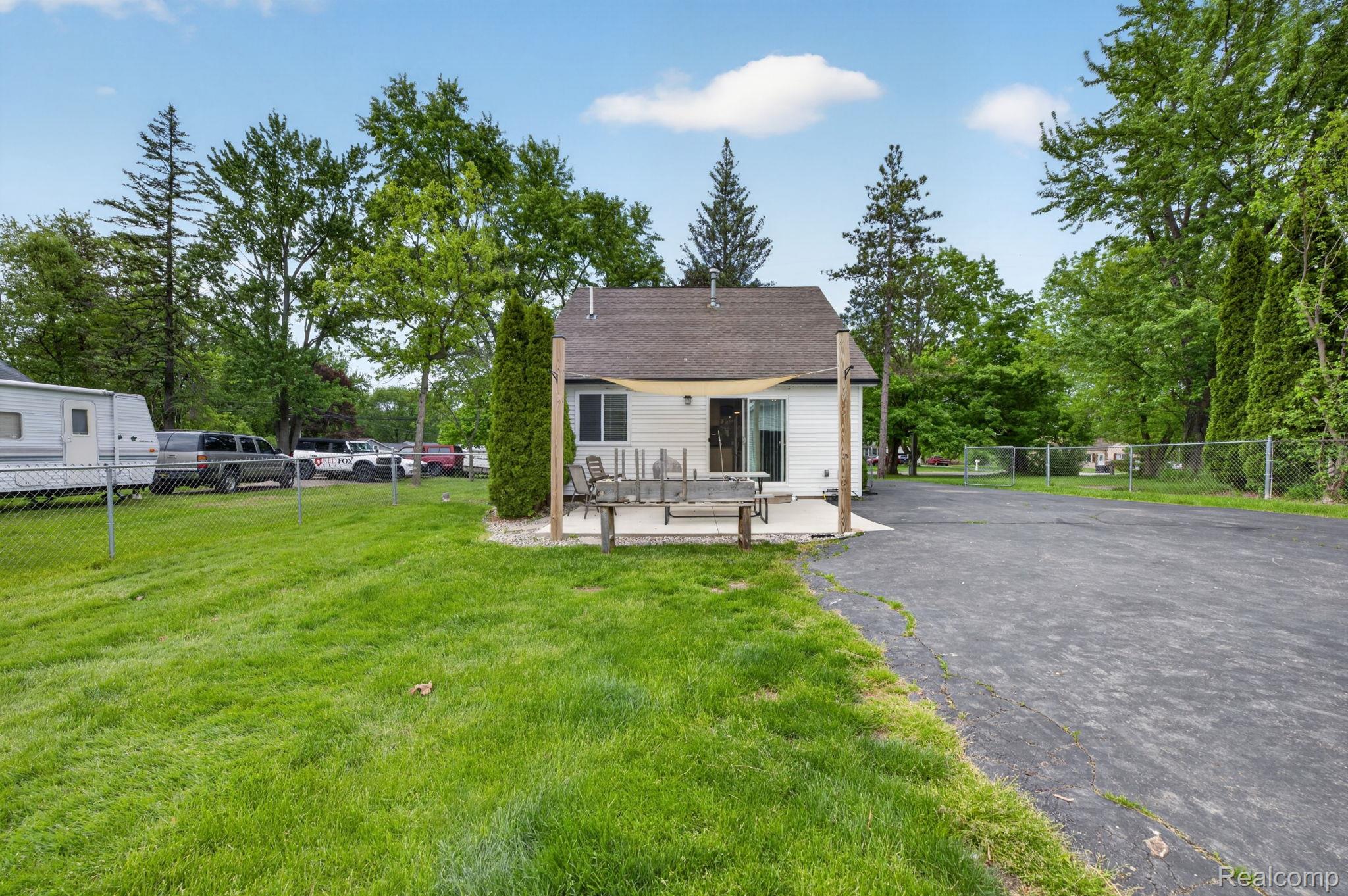 6354 Lapeer Road Burton, MI 48509 - Photo 30 of 44 Back of house with a patio, a shingled roof, and view of scattered trees