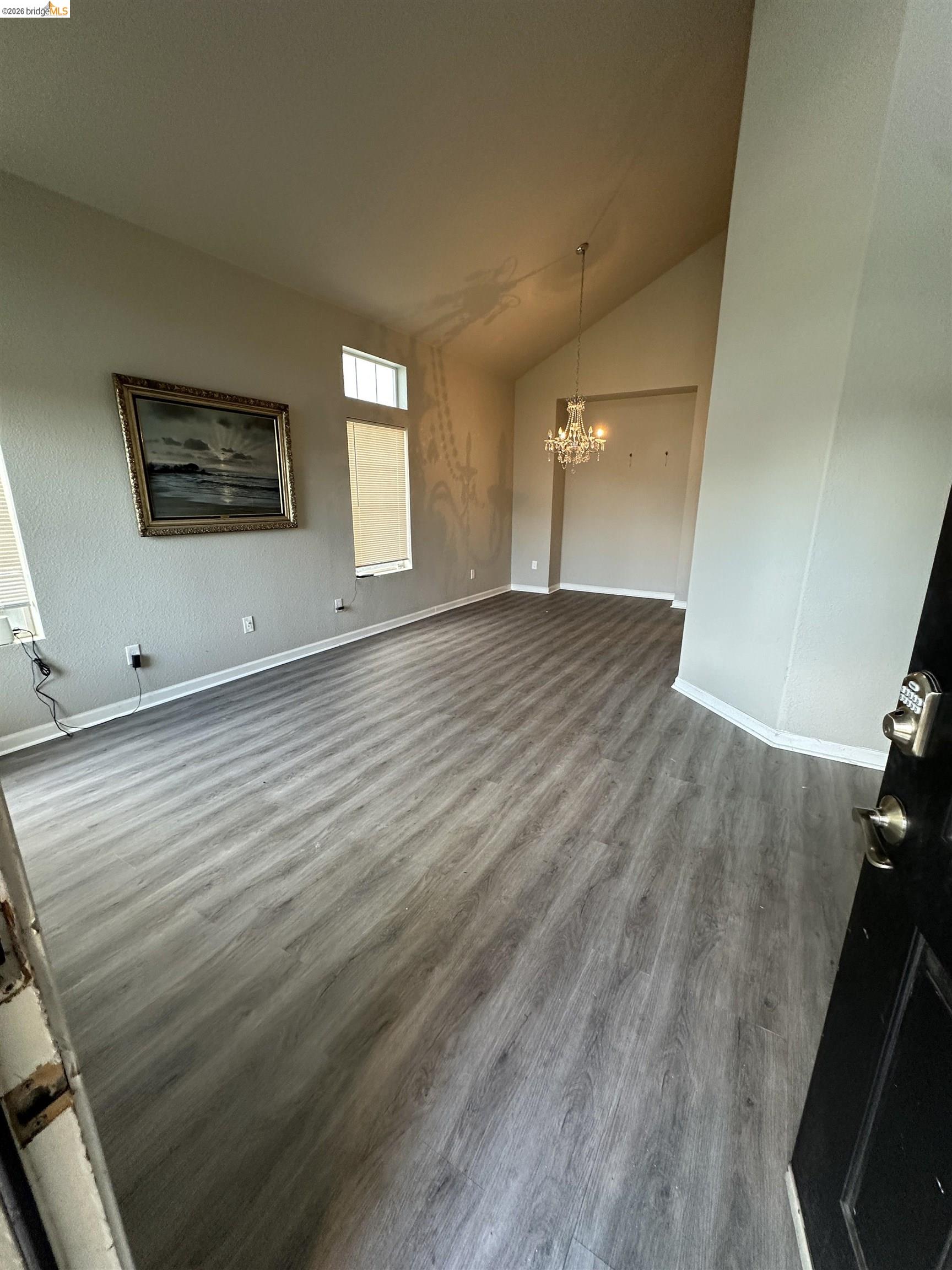 756 Rubier Way Rio Vista, CA 94571 - Photo 4 of 11 Unfurnished living room featuring dark wood-style floors, vaulted ceiling, and hanging lights