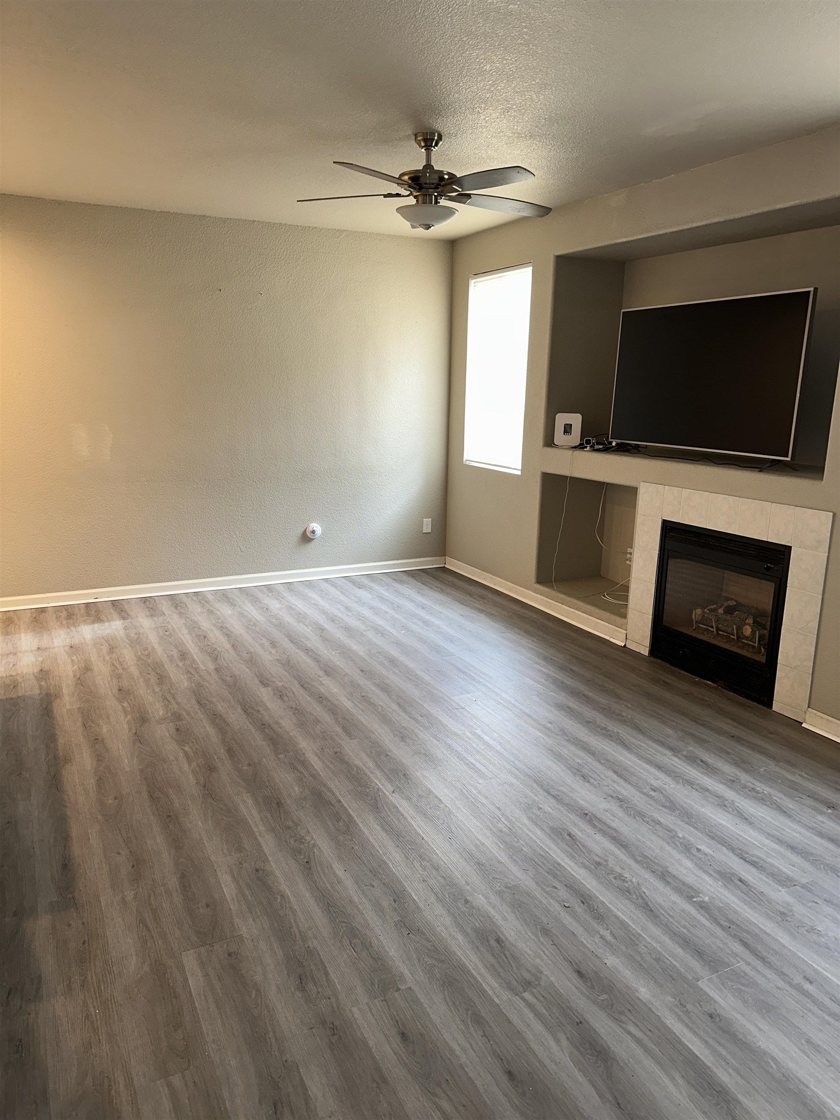 756 Rubier Way Rio Vista, CA 94571 - Photo 9 of 11 Unfurnished living room with wood finished floors, a fireplace, a ceiling fan, and a textured ceiling
