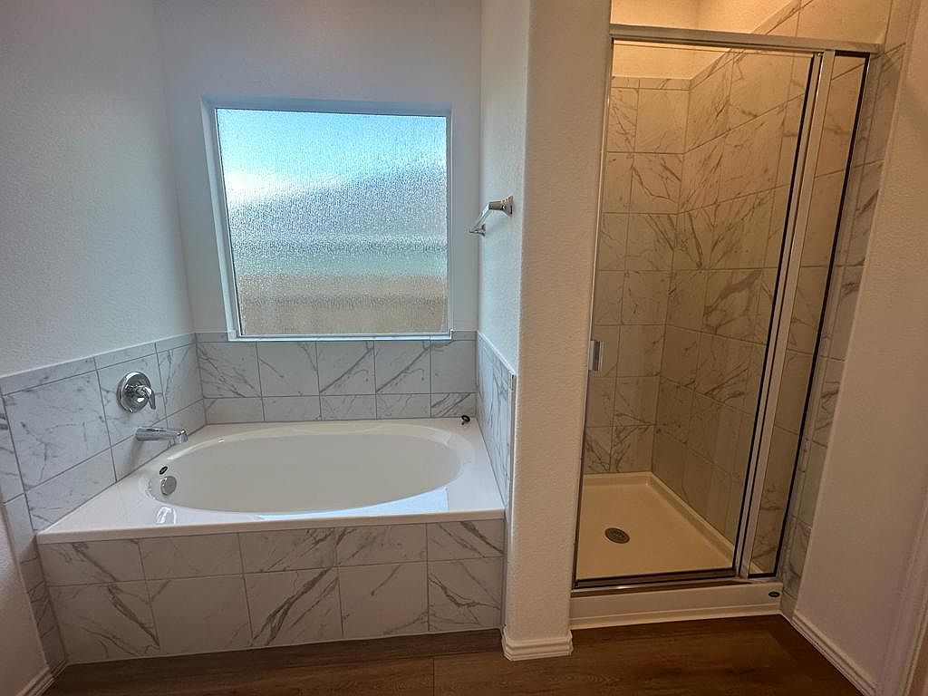 160 River Rise Road Kyle, TX 78640 - Photo 20 of 35 Built-in soaking tub with marble-look tile surround, alongside a glass-enclosed shower featuring coordinating tile and a bronze-finish shower base