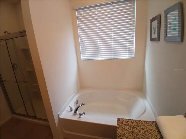 a bed sitting in a bedroom next to a window and a bathroom