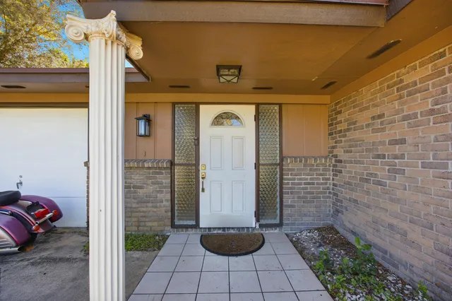 a view of a door of the house with potted plants
