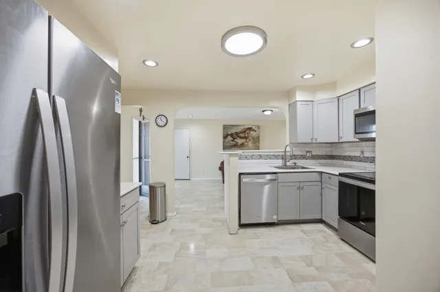 a kitchen with stainless steel appliances granite countertop a refrigerator and a stove top oven