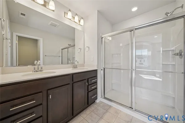 a bathroom with a double vanity sink mirror and shower