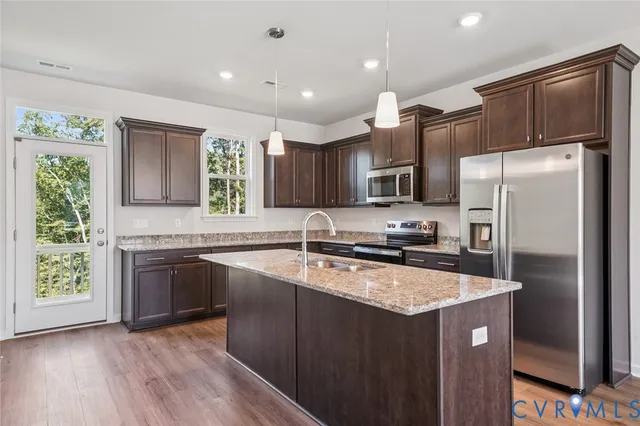 a kitchen with stainless steel appliances granite countertop a sink stove microwave and refrigerator