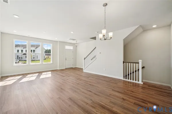 a view of a room with wooden floor chandelier and windows