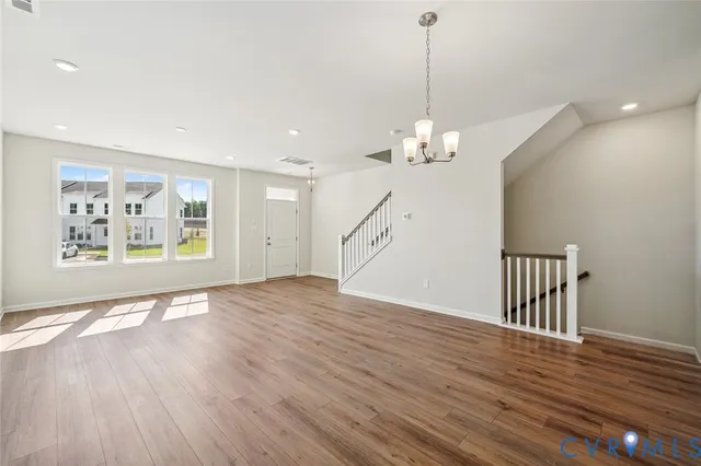 a view of a room with wooden floor chandelier and windows