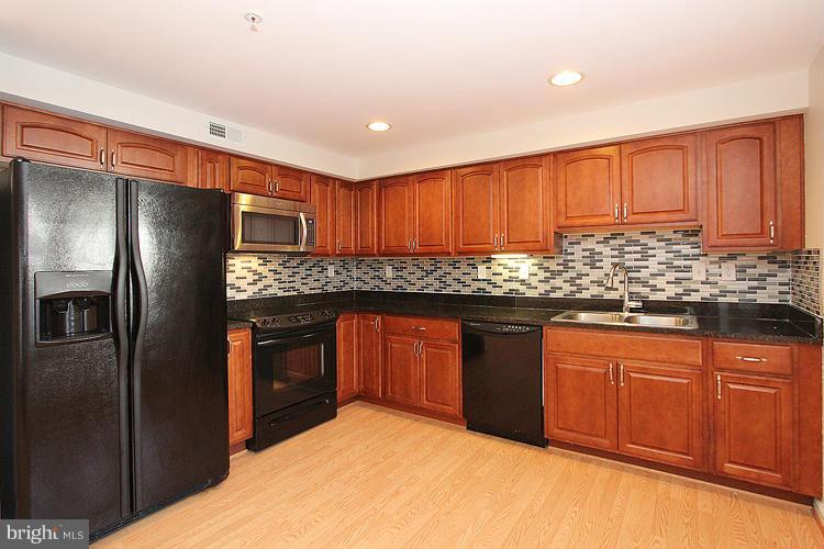 a kitchen with granite countertop stainless steel appliances a refrigerator stove top oven and sink