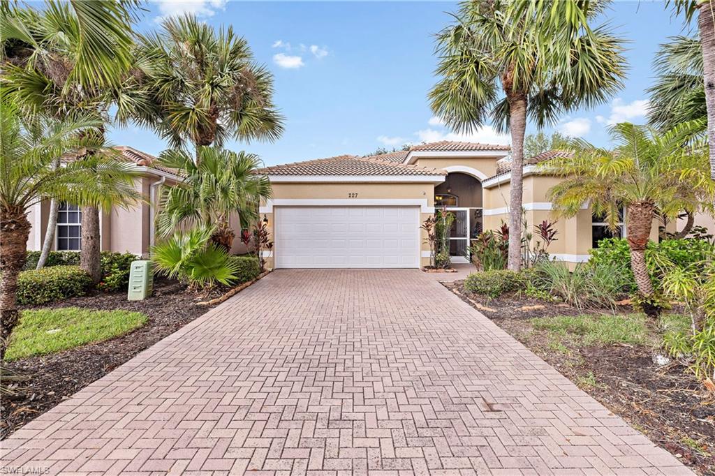 227 Glen Eagle Circle Naples, FL 34104 - Photo 2 of 25 a front view of a house with a garden and palm trees