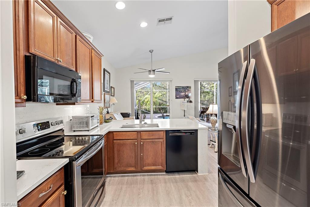 227 Glen Eagle Circle Naples, FL 34104 - Photo 3 of 25 a kitchen with stainless steel appliances a sink stove refrigerator and a window