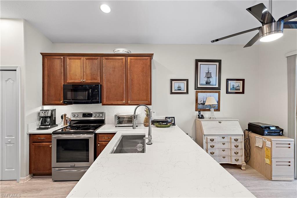 227 Glen Eagle Circle Naples, FL 34104 - Photo 5 of 25 a kitchen with stainless steel appliances a stove a microwave a sink and cabinets