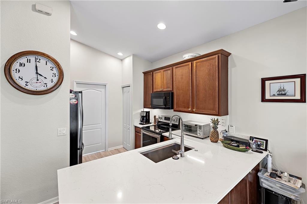 227 Glen Eagle Circle Naples, FL 34104 - Photo 6 of 25 a kitchen with a refrigerator and a stove top oven
