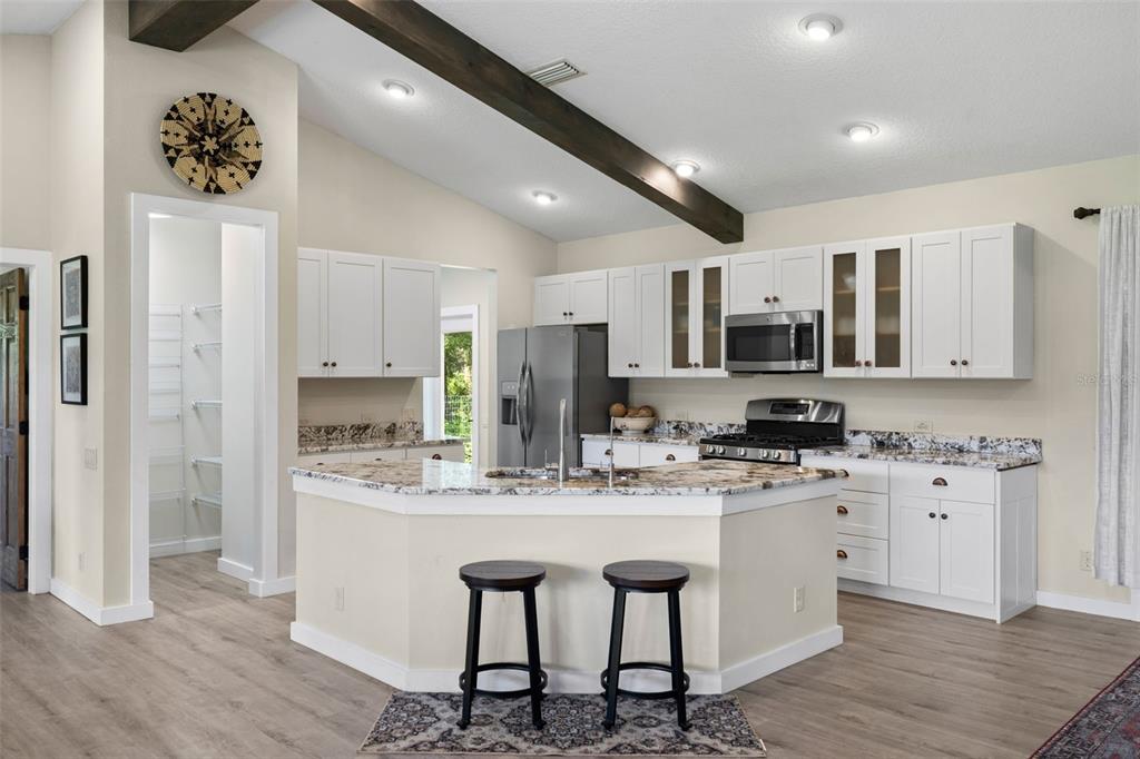 14765 Highway 41 Spring Hill, FL 34610 - Photo 8 of 61 a kitchen with stainless steel appliances kitchen island granite countertop a stove a sink a refrigerator and white cabinets with wooden floor