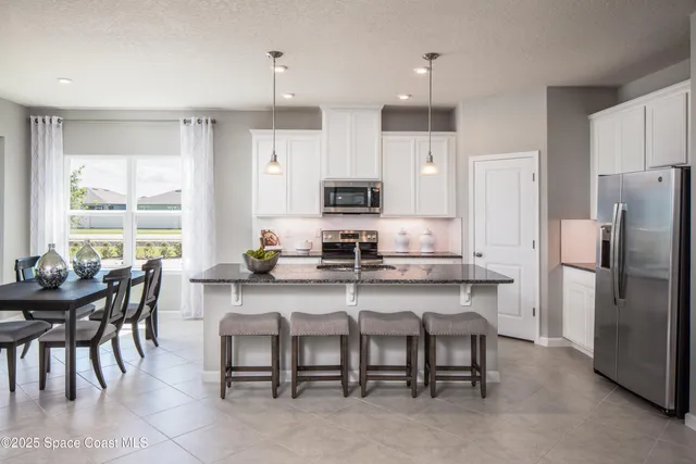 a kitchen with refrigerator a sink and chairs