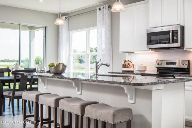 a kitchen with stainless steel appliances granite countertop a table chairs microwave and sink