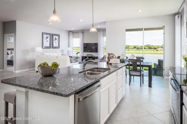 a kitchen with stainless steel appliances granite countertop a sink a stove a dining table and chairs