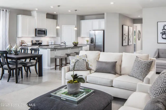 a living room with furniture a kitchen view and a refrigerator