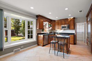372 Stratford Road Des Plaines, IL 60016 - Photo 6 of 13 a kitchen with stainless steel appliances granite countertop a refrigerator a sink dishwasher a stove and a dining table with wooden floor