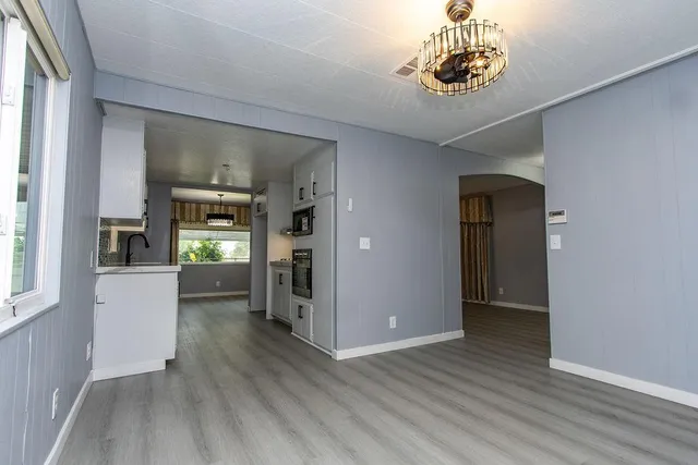 a view of an empty room and kitchen with a window