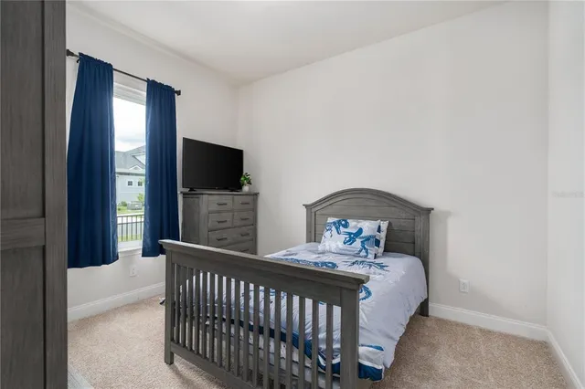 a bedroom with a bed and a flat tv screen on dresser