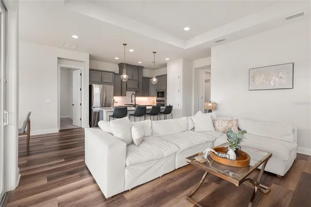 a living room with furniture and a dining table with wooden floor