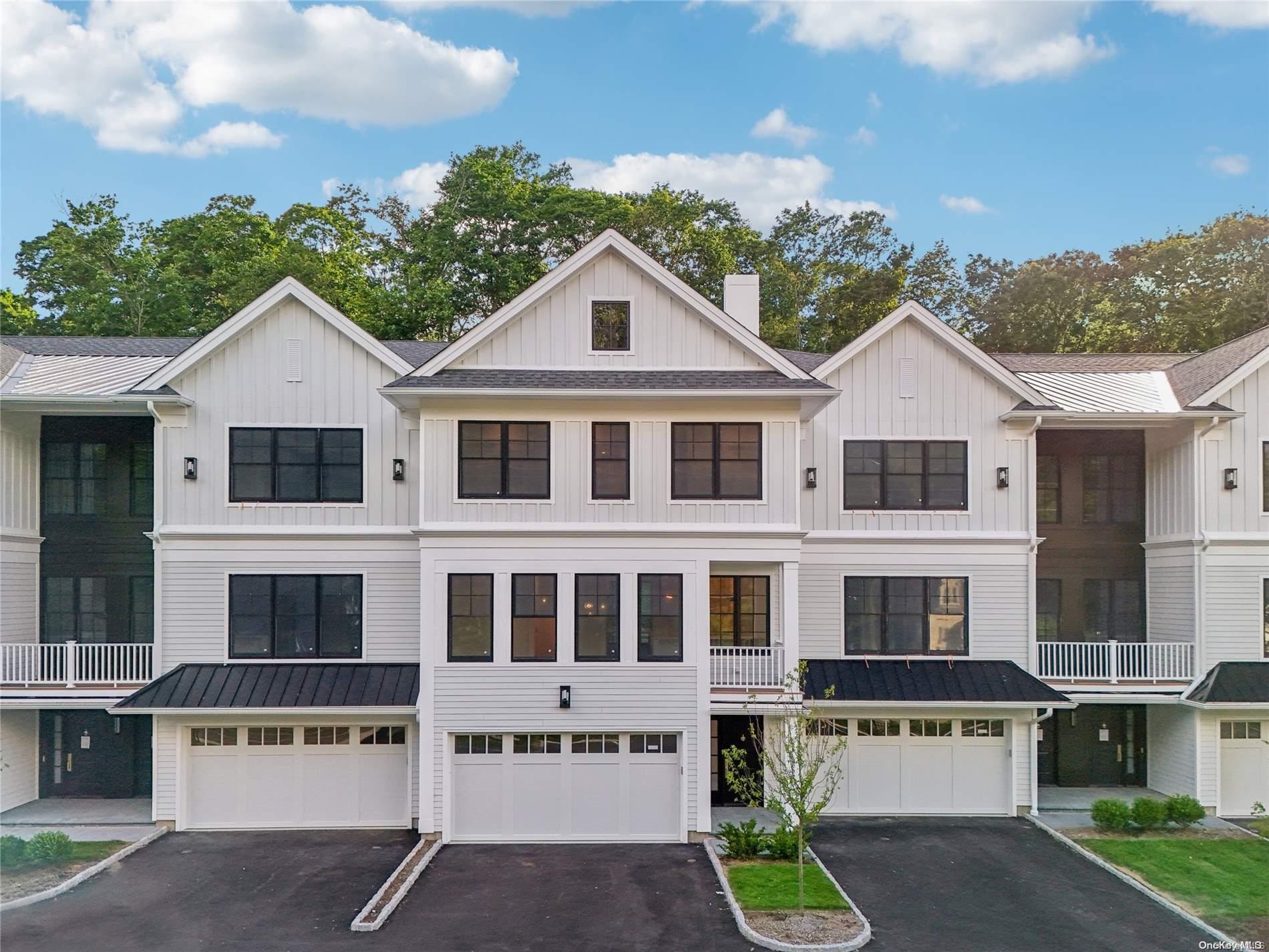 a view of a white house with a large windows and a yard with plants and a table and chairs