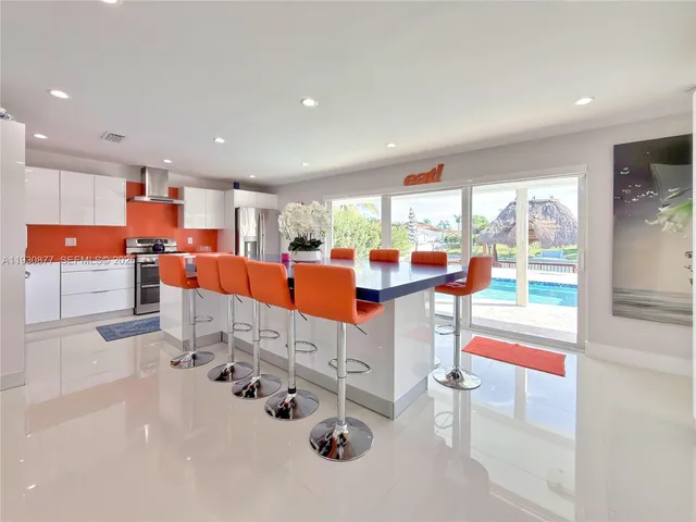 a dining hall with stainless steel appliances kitchen island granite countertop a table and chairs in it