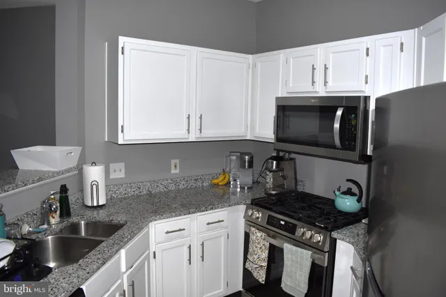 a kitchen with stainless steel appliances granite countertop a sink stove and microwave