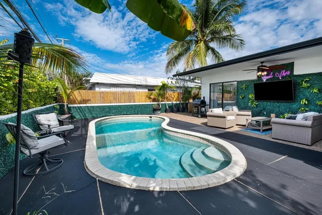 a view of a patio with table and chairs barbeque potted plants and wooden fence