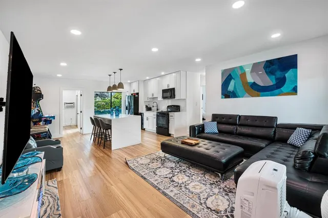 a living room with furniture a flat screen tv and a refrigerator