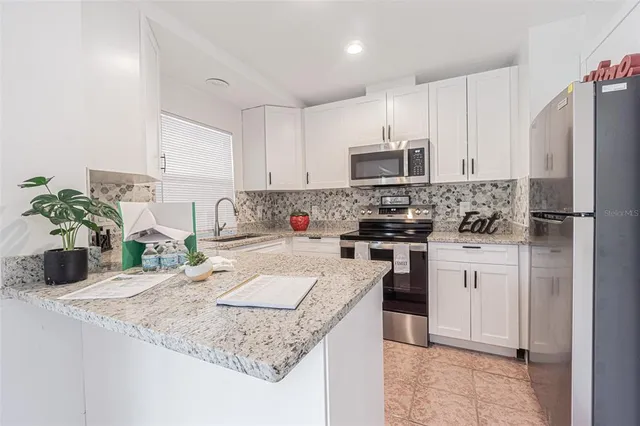 a kitchen with kitchen island granite countertop a sink stove and refrigerator