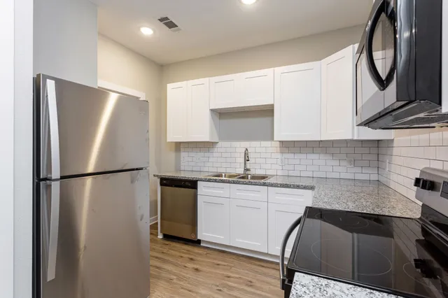 a view of a kitchen with a sink and dishwasher a refrigerator with wooden floor
