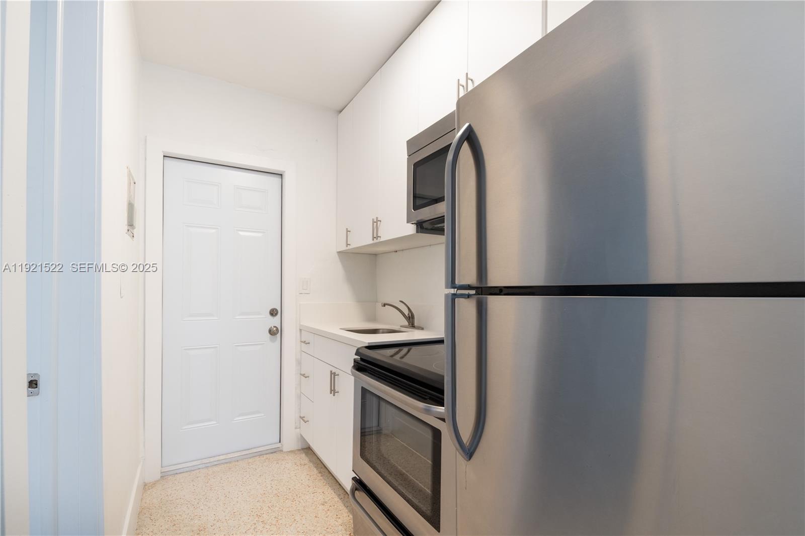 1450 Southwest 6th Street, Unit 1 Miami, FL 33135 - Photo 2 of 7 a kitchen with a refrigerator and white cabinets
