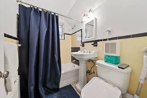 a bathroom with a sink a toilet a mirror and shower curtain