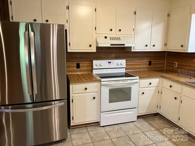 a kitchen with granite countertop a stove a sink and a refrigerator