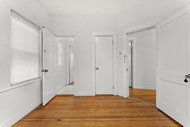 an empty room with wooden floor cabinet and windows