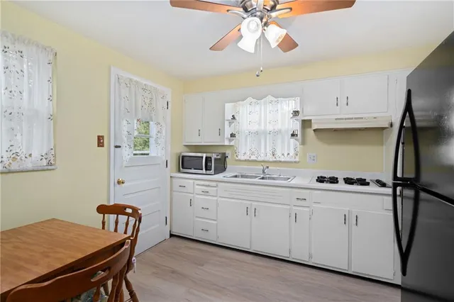 a kitchen with a sink a stove a chandelier cabinetry and a refrigerator