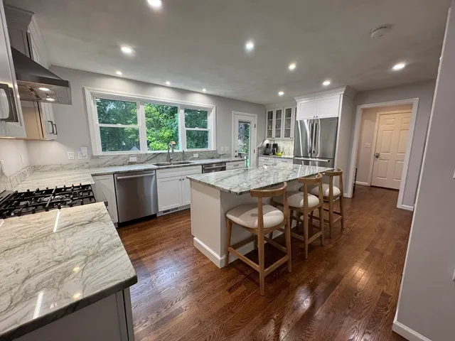 a kitchen with stainless steel appliances granite countertop table chairs and wooden floor