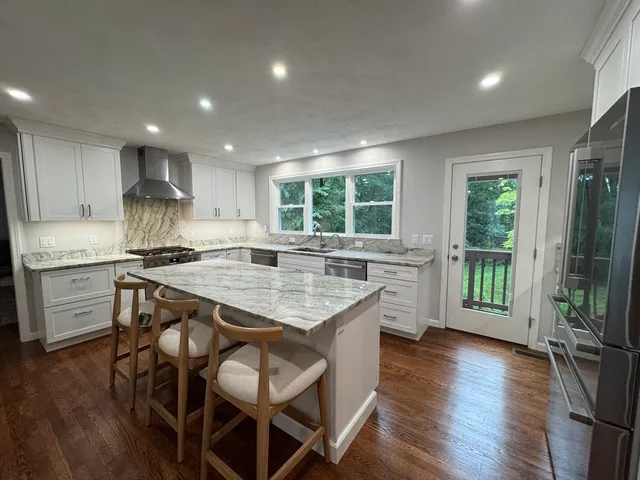 an open kitchen with granite countertop kitchen island wooden floor center island and stainless steel appliances