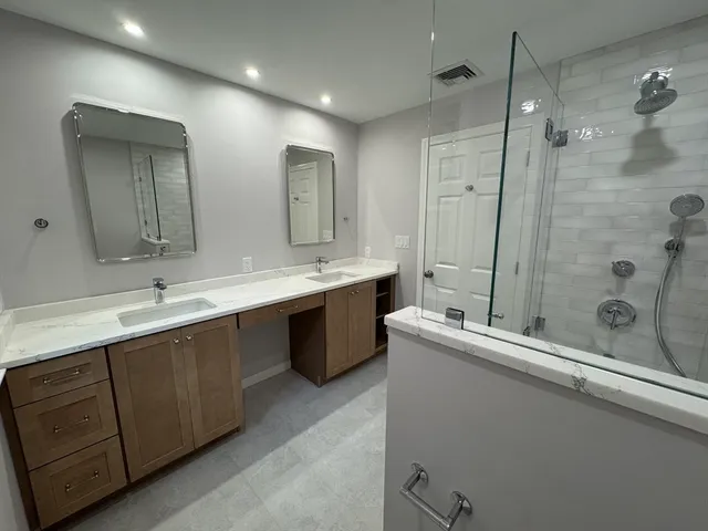 a bathroom with a double vanity sink mirror and shower
