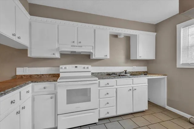 a kitchen with granite countertop a sink and a stove
