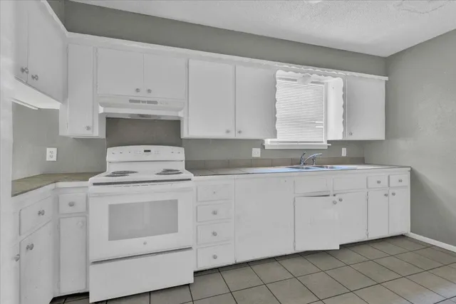 a kitchen with white cabinets appliances and a sink
