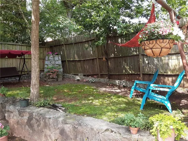 a view of a backyard with table and chairs potted plants and large tree