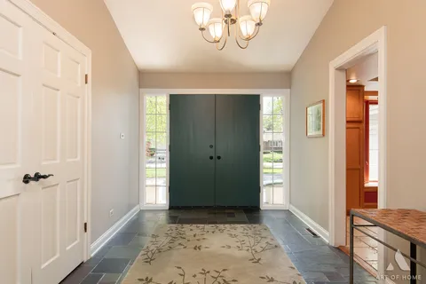 a view of a hallway with wooden floor and a chandelier