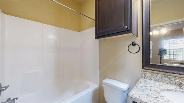 a bathroom with a granite countertop sink toilet and mirror