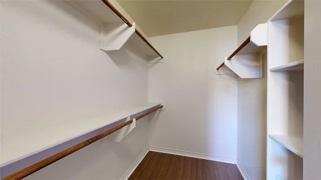an empty room with wooden floor and a ceiling fan
