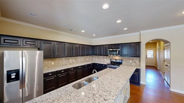 a kitchen with stainless steel appliances granite countertop a stove a sink and a refrigerator