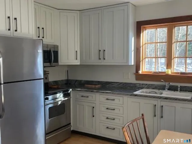 a kitchen with granite countertop white cabinets and white appliances