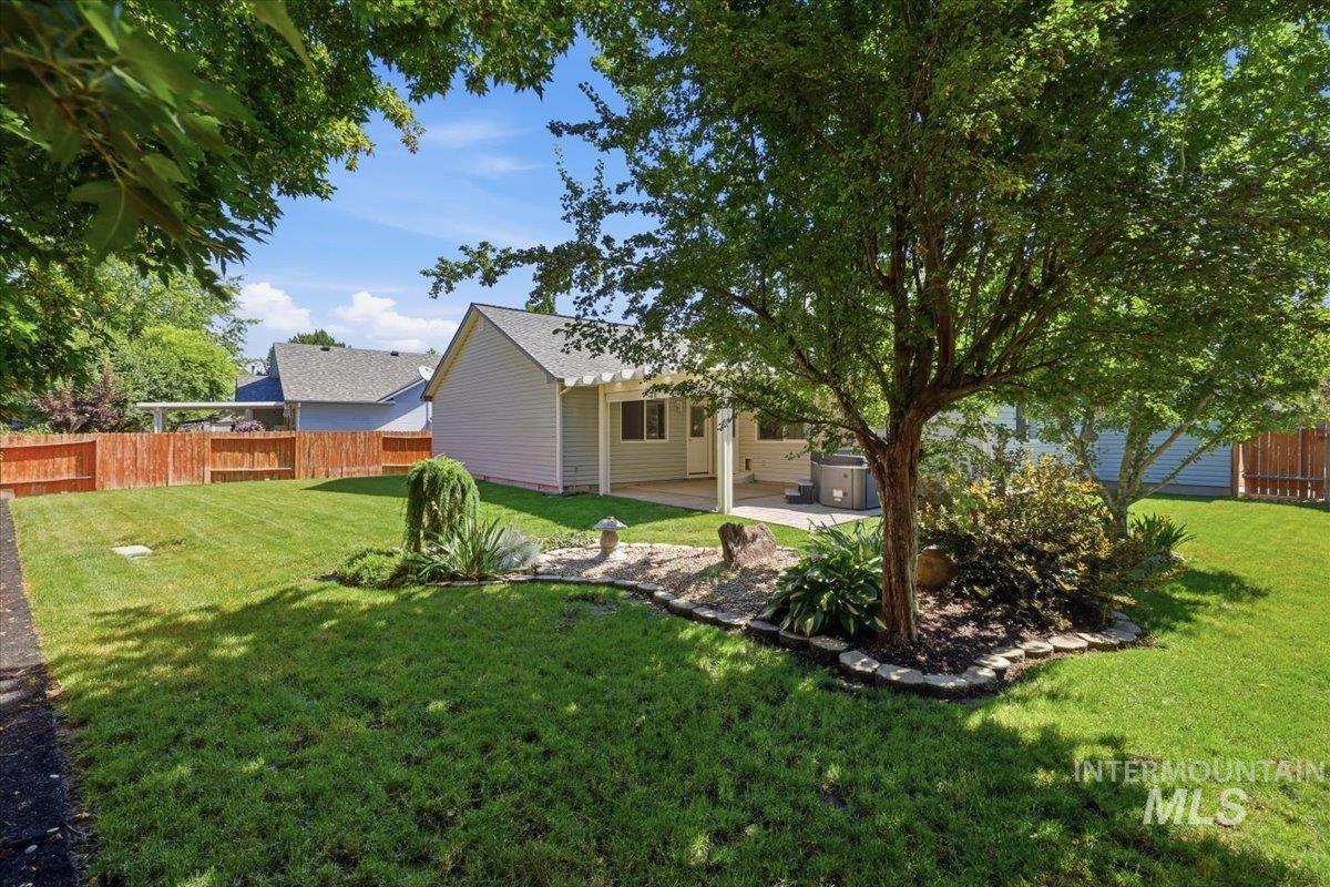 2075 North Springland Place Boise, ID 83713 - Photo 39 of 49 Spacious rear yard with a perimeter wood fence, mature shade tree, shrubbery, and a concrete patio